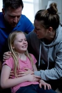 «Τι βρήκατε; Τι βρήκατε;» φώναξα με σπασμένη φωνή, καθώς οι νοσοκόμες σήκωσαν το βλέμμα τους πίσω από τον πάγκο. Το χέρι του Ντέιβιντ άρπαξε το μπράτσο μου σαν νύχι. «Κυρία, σας παρακαλώ, ηρεμήστε. Ας καθίσουμε για λίγο», είπε. Αλλά δεν μπορούσα. «Πείτε μου τι βρήκατε σε εκείνο το σπίτι! Εξηγήστε μου γιατί δίνετε στην κόρη μου ενεργό άνθρακα!» απαίτησα. Ο αστυνομικός —το σήμα του έγραφε Σάτον— αναστέναξε βαθιά. Τα μάτια του δεν έδειχναν απλώς κούραση, αλλά τη σιωπηλή παραίτηση κάποιου που είχε δει τα χειρότερα της ανθρώπινης ψυχής. «Ερευνήσαμε το σπίτι της κυρίας Όλμπραϊτ», είπε με χαμηλή, συγκρατημένη φωνή. «Ήταν… σιωπηλό. Μια ανησυχητική σιωπή. Όταν μπήκαμε, καθόταν στην πολυθρόνα της και παρακολουθούσε ένα τηλεπαιχνίδι.» «Ένα… τηλεπαιχνίδι;» ψιθύρισε ο Ντέιβιντ, δύσπιστος. «Δεν έδειξε καμία έκπληξη που μας είδε», συνέχισε ο Σάτον. «Αρχίσαμε να ερευνούμε την κουζίνα. Κυρία… οι συνθήκες ήταν ανησυχητικές. Το πρώτο πράγμα που μας χτύπησε ήταν η μυρωδιά. Βρήκαμε δεκάδες κονσέρβες, με ημερομηνίες λήξης από τη δεκαετία του ’80. Μερικές, ακόμα και από τη δεκαετία του ’70.» Ένιωσα το αίμα να φεύγει από το πρόσωπό μου. «Ω, Θεέ μου. Θεέ μου…» «Αλλά αυτό δεν ήταν το ζητούμενο. Με βάση την τοξικολογική αναφορά, ψάχναμε κάτι συγκεκριμένο. Το βρήκαμε στο φαρμακείο της, αλλά και στο ντουλάπι, κρυμμένο μέσα σε ένα βάζο με αλεύρι.» Έβγαλε ένα μικρό σημειωματάριο από την τσέπη της, αν και δεν χρειάστηκε να το κοιτάξει. Το ήξερε απ’ έξω. «Βρήκαμε αρκετά μπουκαλάκια με ληγμένα φάρμακα. Όμως ένα συγκεκριμένο τράβηξε την προσοχή μας. Ένα φάρμακο που έχει ανακληθεί στις Ηνωμένες Πολιτείες εδώ και πάνω από είκοσι χρόνια. Ένα ισχυρό φάρμακο… που, μόλις λήξει, μετατρέπεται σε μια εξαιρετικά τοξική και διαβρωτική ουσία.» Οι λέξεις της με χτύπησαν σαν μαχαίρι. «Διαβρωτική; Τι… τι σημαίνει αυτό;» κατάφερα να ψελλίσω. «Έχουμε λόγους να πιστεύουμε —και επιβεβαίωση— ότι τα χάπια αυτά τα θρυμμάτισε και τα ανακάτεψε σκόπιμα στο φαγητό που προοριζόταν για την κόρη της.» Ο κόσμος μου κατέρρευσε. Τα φώτα φθορισμού τρεμόπαιξαν σαν σιωπηλή κραυγή. Ο Ντέιβιντ έκανε μερικά βήματα πίσω, μέχρι που στήριξε την πλάτη του στον τοίχο. «Αλλά… γιατί;» Η φωνή του ήταν ένας σπασμένος ψίθυρος. «Γιατί να το κάνει; Η Έμιλι την αγαπούσε. Την εμπιστευόμασταν. Την ξέραμε δέκα χρόνια! Γιατί;» Ο πράκτορας Σάτον με κοίταξε. Το βλέμμα του δεν ήταν πια επαγγελματικό· υπήρχε κάτι πιο σκοτεινό, μια ερευνητική περιέργεια. «Την ρωτήσαμε κι εμείς», είπε τελικά. «Στην αρχή δεν μίλησε. Συνέχισε να βλέπει τηλεόραση. Μετά γύρισε το κεφάλι της, κοίταξε τον συνάδελφό μου και είπε: “Ήταν εξαιτίας της Έμμα.” Είπε το όνομά σας, κυρία.» «…εξαιτίας μου;» Έκανα ένα βήμα πίσω, σαν να με είχαν χτυπήσει. «Τι σχέση έχω εγώ μ’ αυτό;» «Την ανακρίναμε ξανά», είπε η Σάτον με σκυθρωπή φωνή. «Είπε μια ιστορία. Κάτι που, όπως ισχυρίζεται, συνέβη πριν από χρόνια. Είπε: “Η Έμμα την άφησε να πεθάνει.” Ισχυρίστηκε πως αρνηθήκατε να τη βοηθήσετε όταν ο άντρας της ήταν άρρωστος και ότι… αυτό… ήταν δικαιοσύνη.» Ο διάδρομος γύρισε γύρω μου. «Αρνήθηκα… να τη βοηθήσω;» επανέλαβα, ψάχνοντας να καταλάβω. Και τότε, σαν να με χτύπησε κάτι βαρύ, η ανάμνηση επέστρεψε. Δεν ήταν «πολύ παλιά». Ήταν πριν τρία χρόνια. Τρία ακριβώς. Ο σύζυγος της Μάργκαρετ, ο Άρθουρ, ήταν άρρωστος. Όχι απλώς άρρωστος — πέθαινε. Ένας επιθετικός, ανελέητος καρκίνος. Μέσα στην απόγνωσή της, η Μάργκαρετ άρχισε να ψάχνει εναλλακτικές «θεραπείες»… όχι ιατρικές, αλλά διαδικτυακές απάτες. Η ανάμνηση ξαναζωντάνεψε, με τη μυρωδιά της βροχής και του φόβου. Μια βροχερή Τρίτη. Η Μάργκαρετ ήρθε στην πόρτα μου, μουσκεμένη, τα μάτια της διάπλατα. Κρατούσε ένα εκτυπωμένο άρθρο. «Έμμα, σε παρακαλώ», είπε τρέμοντας. «Είναι μια νέα θεραπεία από μια κλινική στη Γερμανία. Έχει ποσοστό επιτυχίας 90%! Αλλά είναι ακριβή. Πρέπει να στείλουμε τα χρήματα σήμερα.» Κοίταξα το χαρτί. Ήταν ξεκάθαρη απάτη: θολές φωτογραφίες, υποσχέσεις-θαύματα, και αίτημα για αποστολή 15.000 δολαρίων σε λογαριασμό χωρίς στοιχεία. «Μάργκαρετ…» είπα απαλά, ενώ της έφτιαχνα λίγο τσάι. «Αυτό δεν φαίνεται αληθινό. Νομίζω πως είναι απάτη. Ας καλέσουμε τον γιατρό του Άρθουρ, ας ζητήσουμε βοήθεια από το νοσοκομείο…» Το πρόσωπό της πάγωσε. Η απελπισία μετατράπηκε σε θυμό. «Δεν θέλεις να με βοηθήσεις», είπε πικρά. «Προσπαθώ να σε βοηθήσω», είπα. «Θέλω να σε προστατεύσω από αυτούς.» «Έχετε λεφτά», ρουθούνισε. «Εσύ κι ο Ντέιβιντ. Το καινούργιο σου αυτοκίνητο, οι διακοπές σου. Τα έχεις. Απλώς δεν θέλεις. Τον αφήνεις να πεθάνει.» Πέταξε το φλιτζάνι στο σκαλί της πόρτας. Έσπασε σε χίλια κομμάτια. Έφυγε μέσα στη βροχή και δεν μου ξαναμίλησε ποτέ. Μέχρι τώρα. Ο Άρθουρ πέθανε δύο εβδομάδες αργότερα. Νόμιζα πως η απομάκρυνσή της ήταν από τη θλίψη. Της έστειλα φαγητό, ένα σημείωμα. Όλα γύρισαν πίσω, σφραγισμένα. Κι έτσι, απλώς σταματήσαμε να προσπαθούμε. «Θεέ μου…» ψιθύρισα με λυγμούς, γλιστρώντας στον τοίχο μέχρι που κάθισα στο πάτωμα. «Ήταν απάτη. Ήθελε λεφτά για μια ψεύτικη θεραπεία. Είπα όχι. Προσπάθησα να τη σώσω.» Κι εκείνη… το ερμήνευσε ως προδοσία.